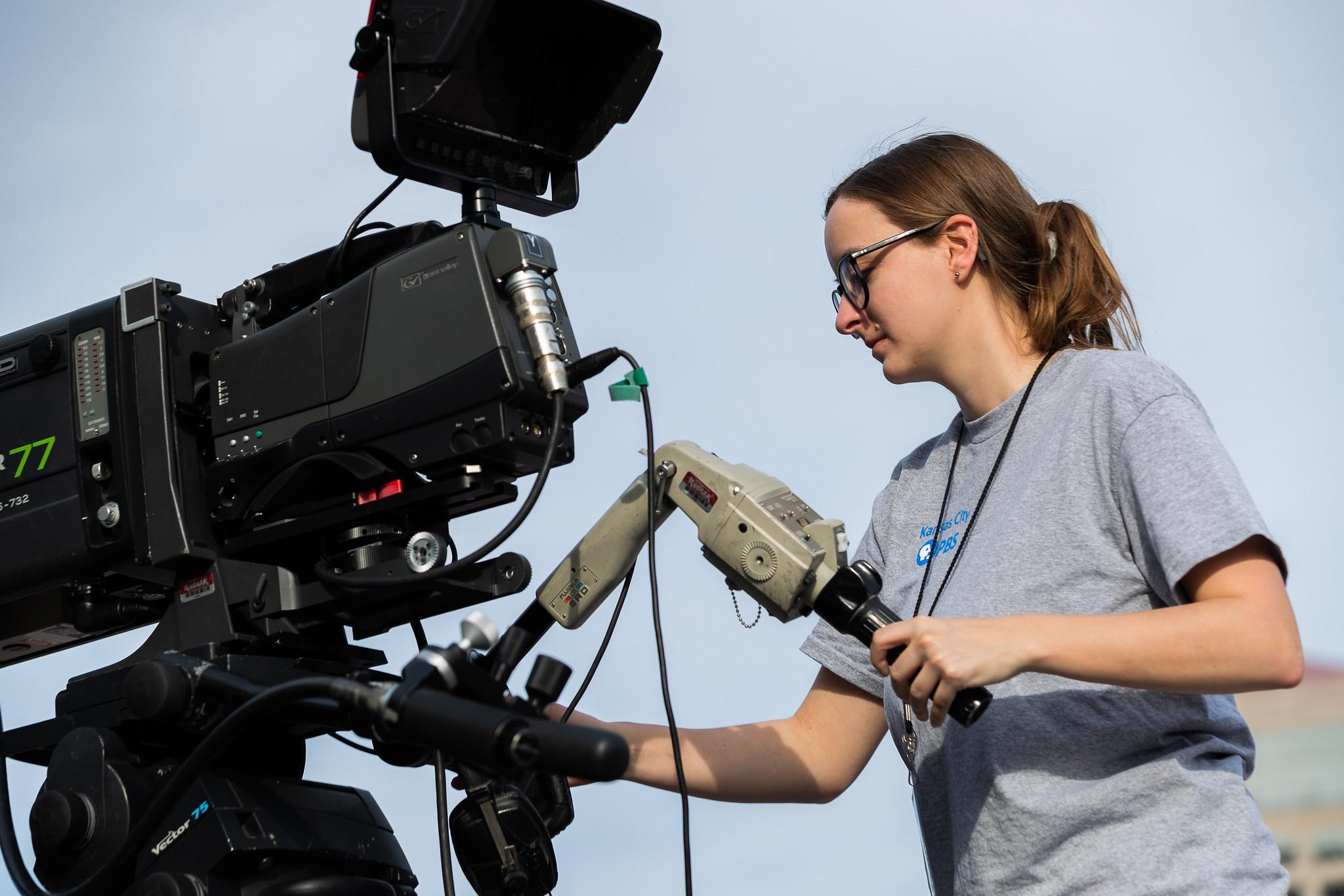 A young woman operates a TV camera.