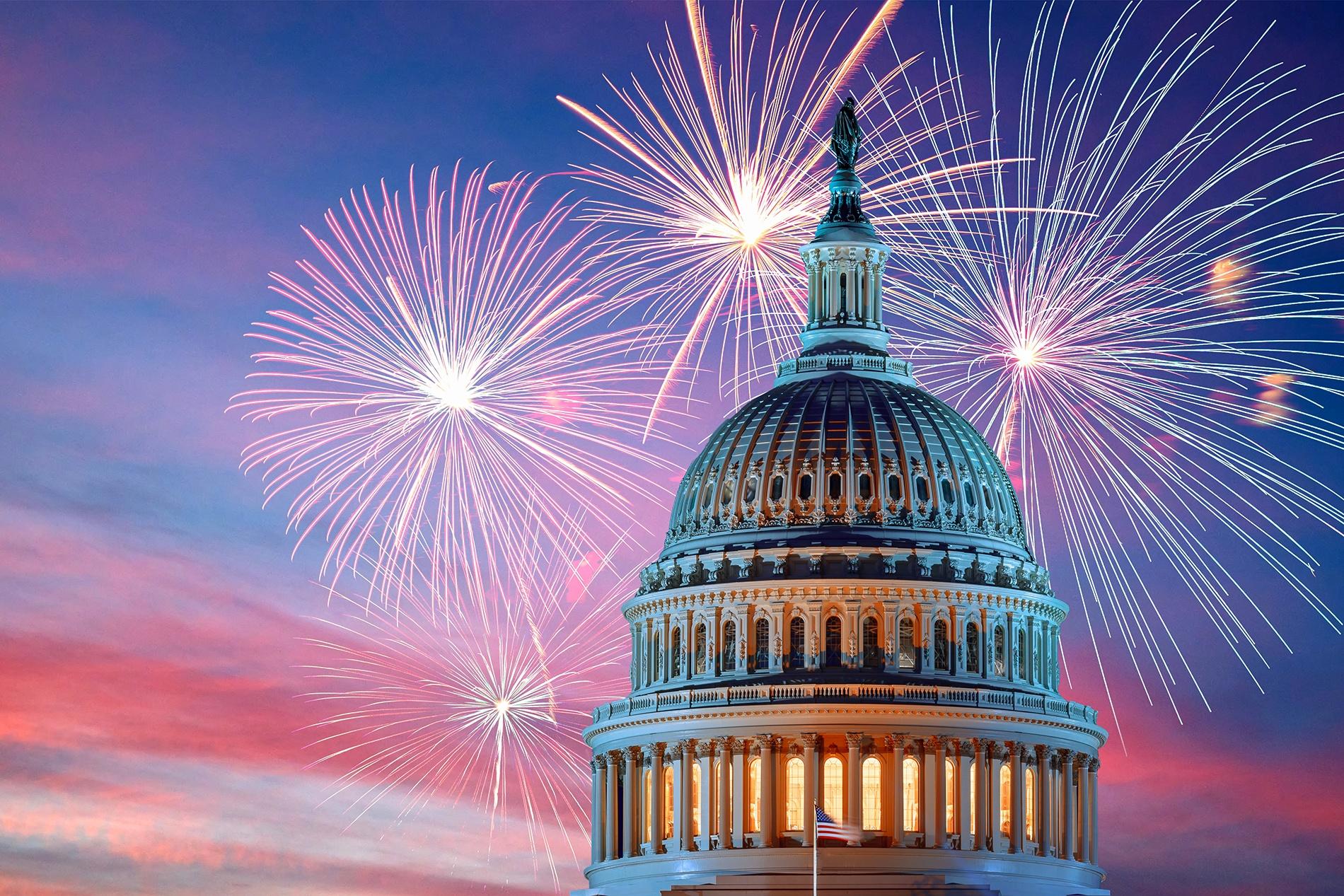 The United States Capitol building with its iconic dome is illuminated against a vibrant twilight sky. Bright, colorful fireworks explode in the background, creating a festive and celebratory atmosphere—capturing the spirit of PBS’s A Capitol Fourth Independence Day celebration.