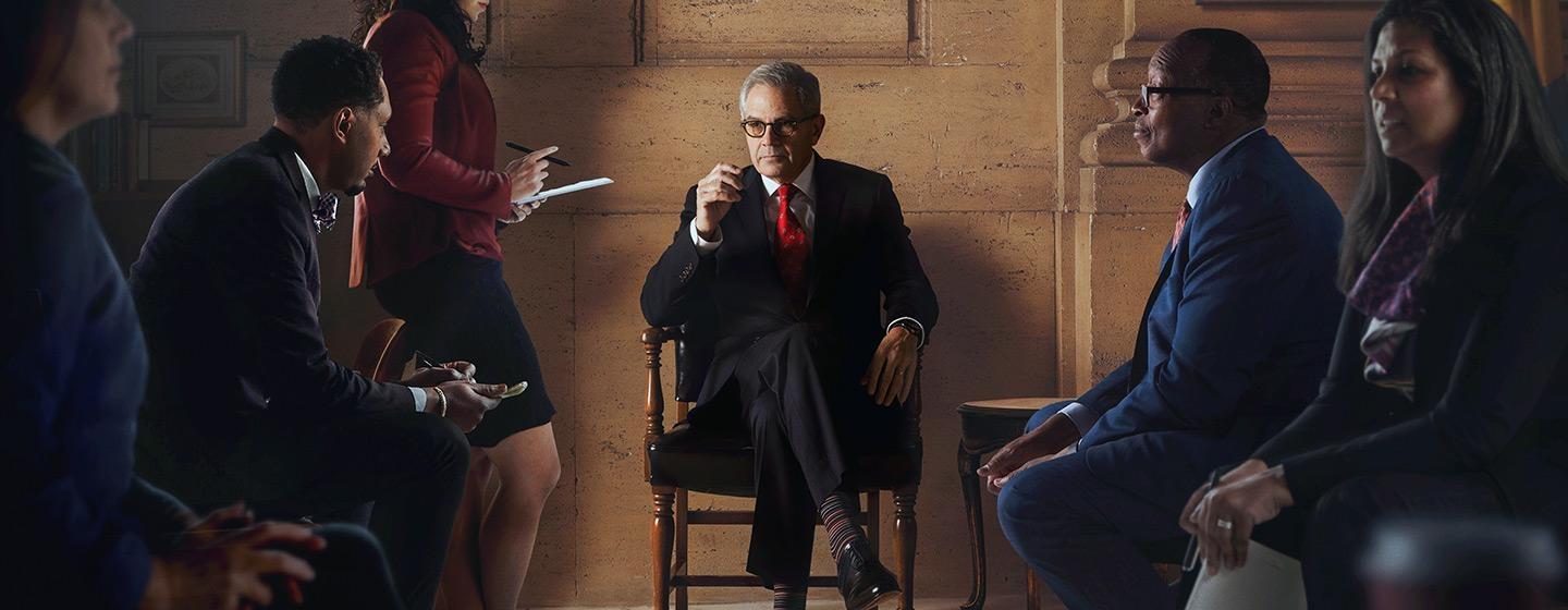 Larry Krasner sits surrounded by reporters.