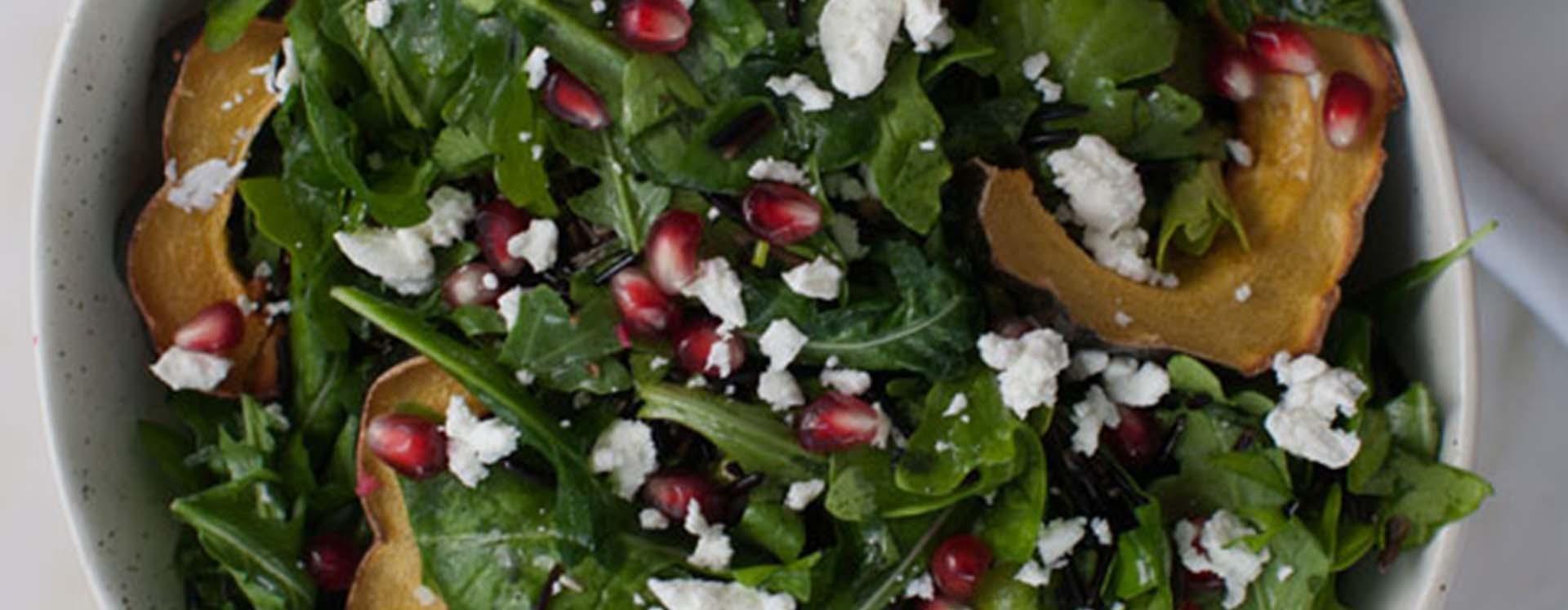 A salad with pomegranate, goat cheese, and acorn squash.