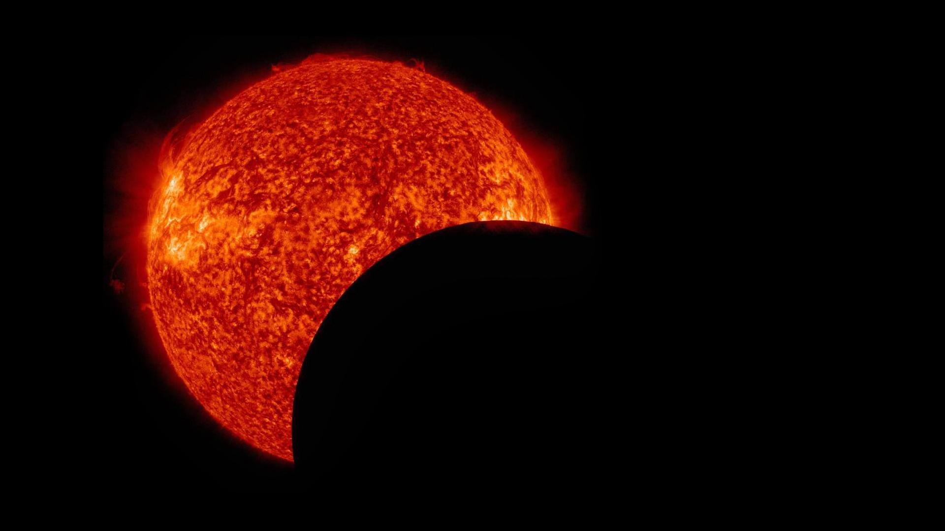 A dark circle (the moon) moves in front of the sun during an eclipse