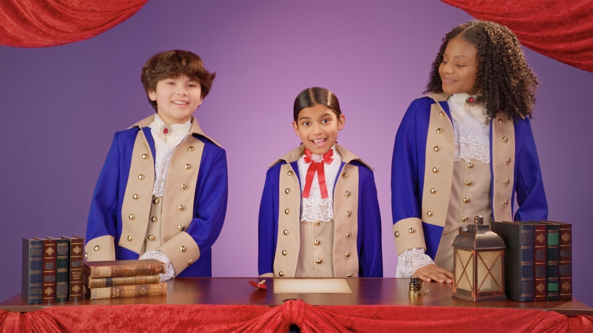 three children dressed in 17th century costumes smile at the camera as they explain Constitution Day 