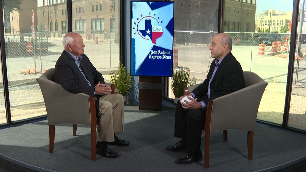 Texas Talk host Gilbert Garcia and State Rep. Diego Bernal sit opposite one another in two chairs. Between them, the "Texas Talk" logo is displayed on a screen. 