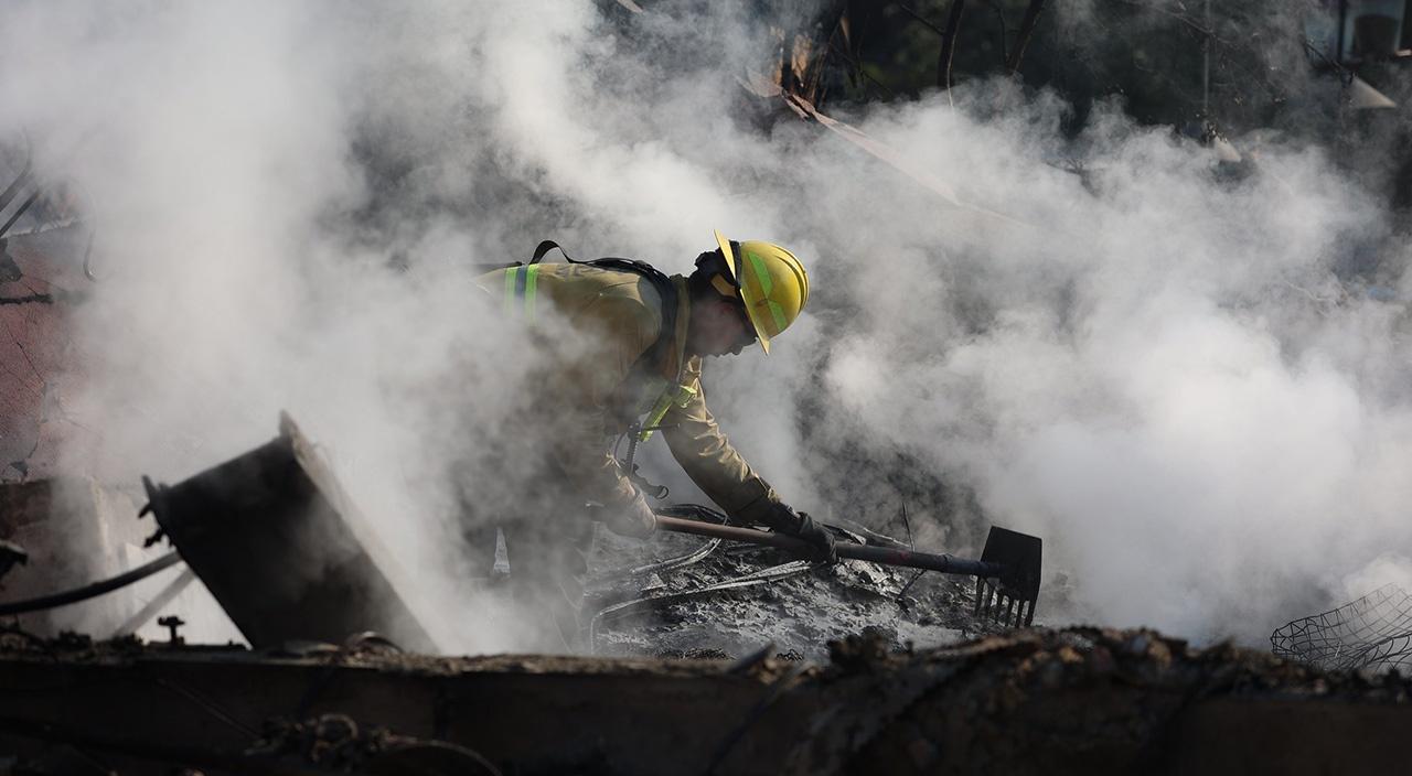 Firefighter digging through rubble while engulfed in smoke