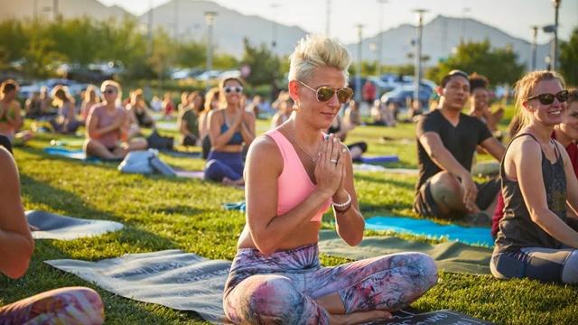 Yoga practitioners sitting on mats on an outdoor lawn