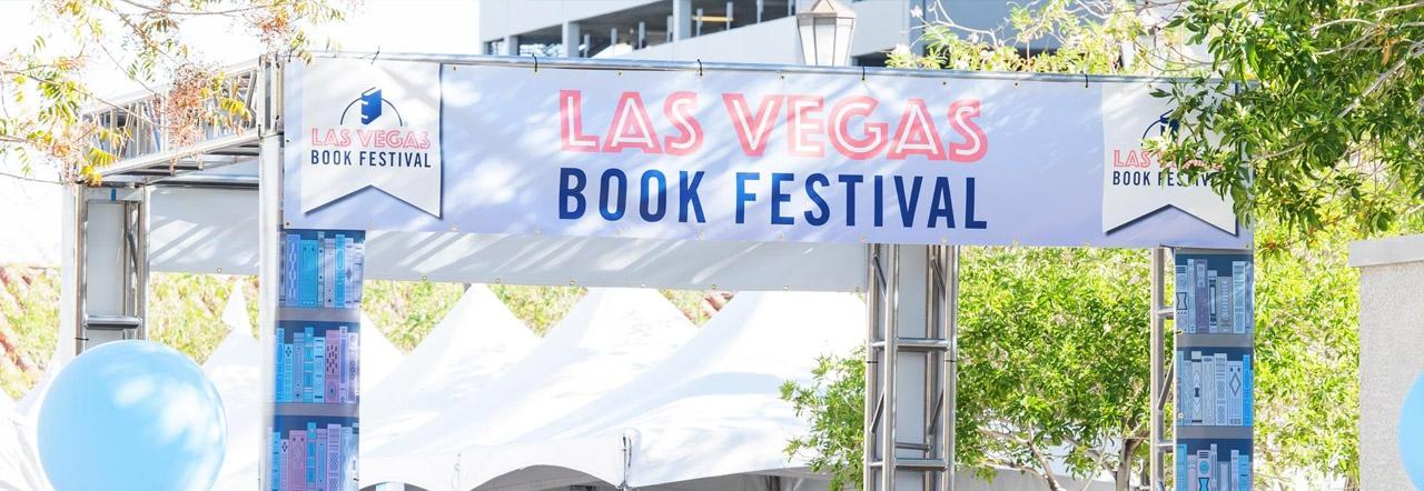 Las Vegas Book Festival banner outside on a sunny day with tents in the background