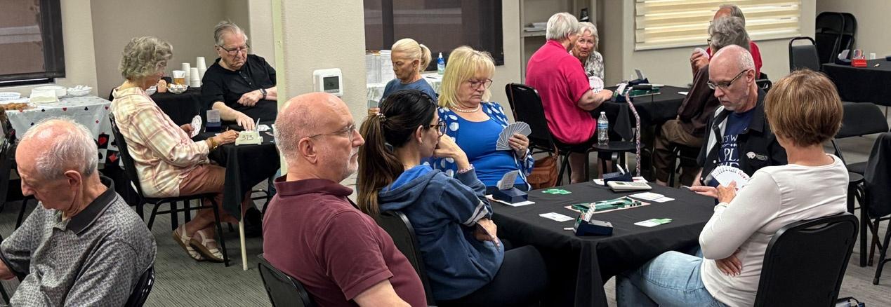 several tables playing bridge card game in a community center room