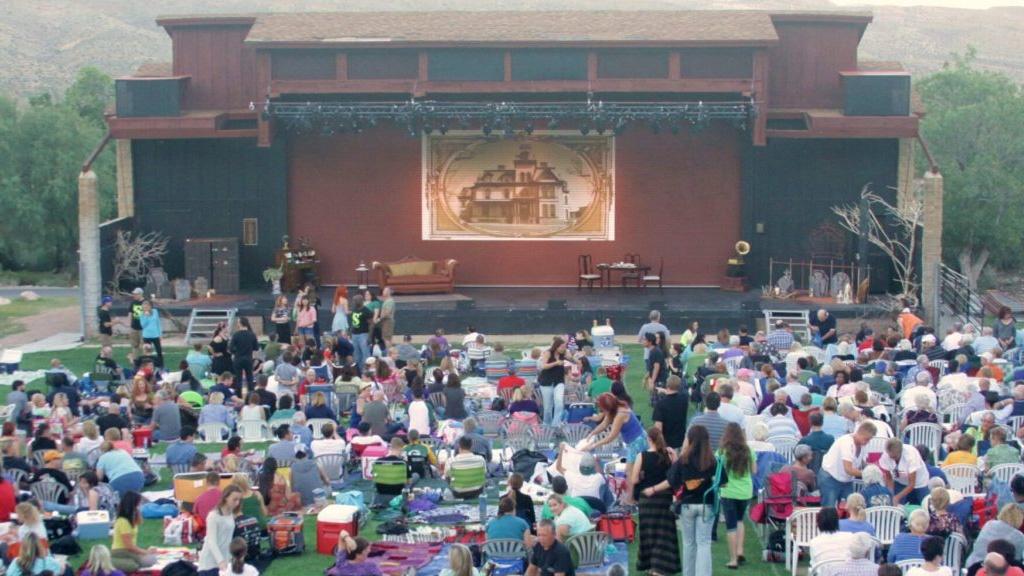 Outdoor stage with crowd sitting on the lawn in the foreground