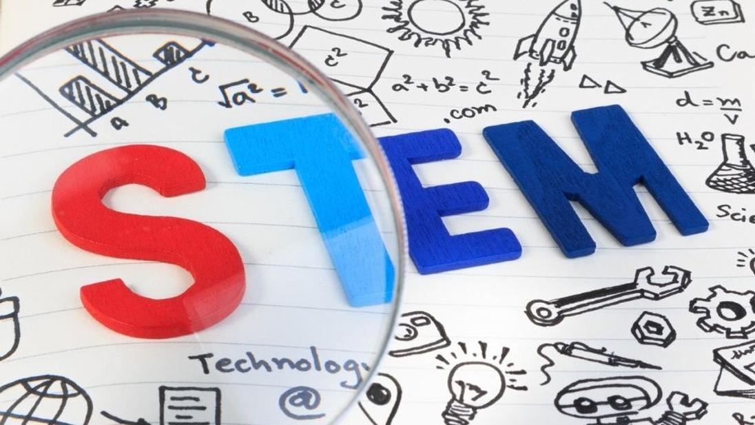 STEM in multicolored letters as seen through a magnifying glass against an illustrated background of science-related images