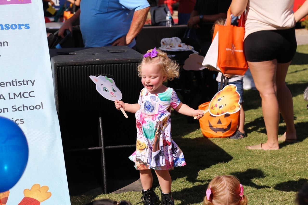 A child walks in a festival field carrying fans of Daniel Tiger characters