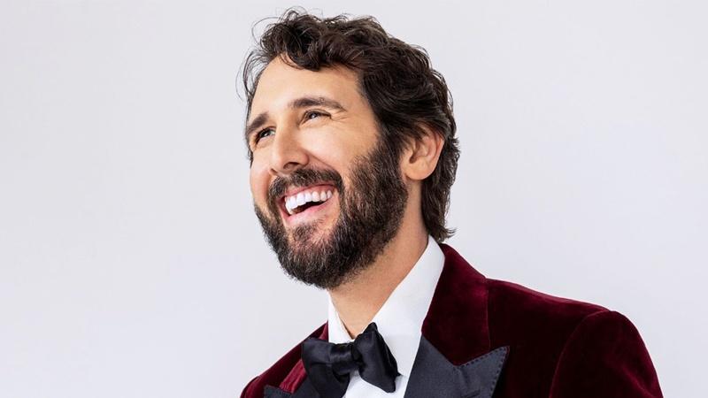 Josh Groban smiling while wearing a red velvet tuxedo