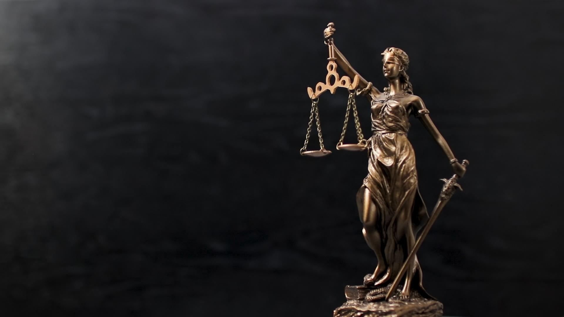 bronze statuette of Lady Justice against a black background