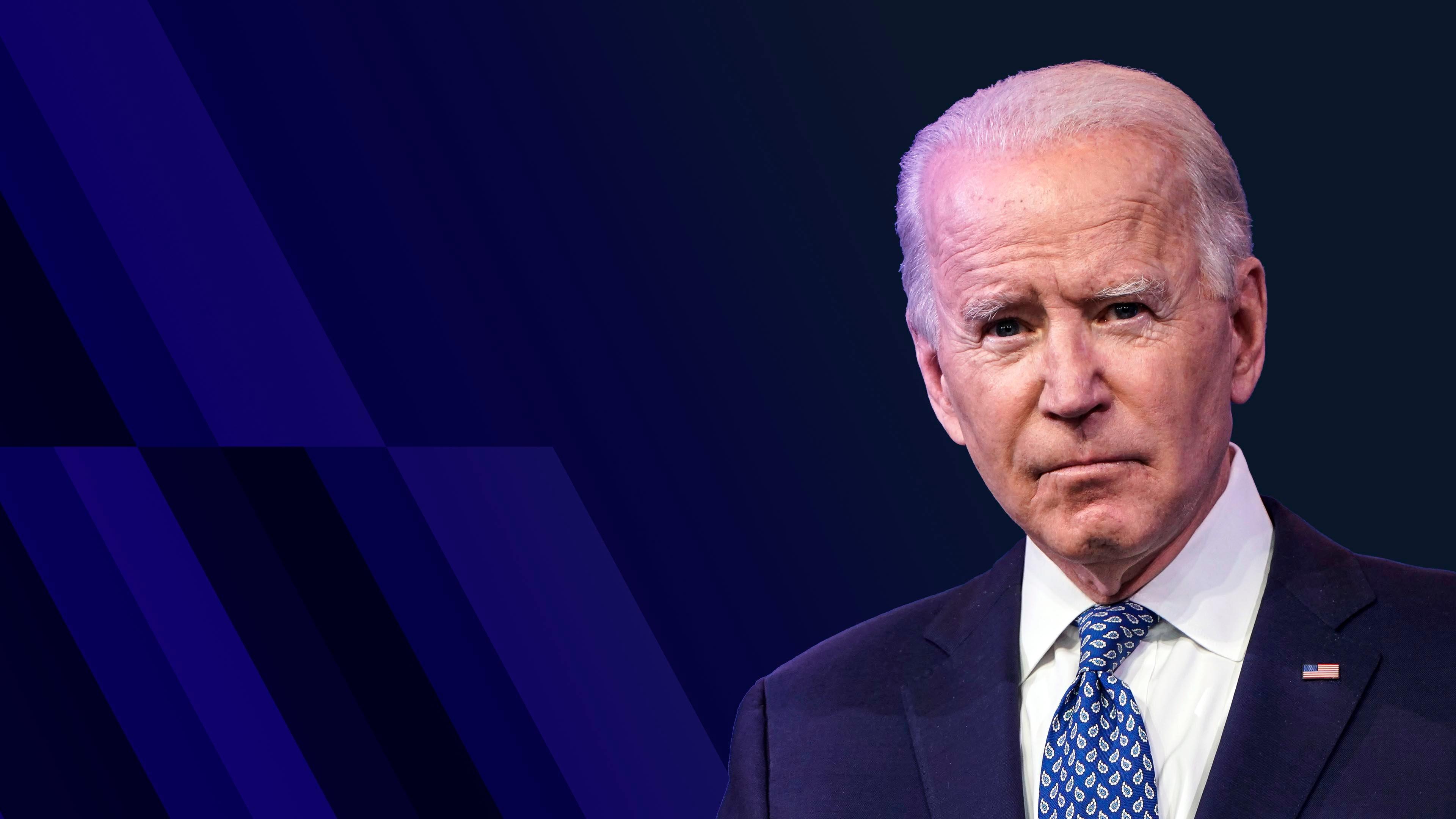 President Joe Biden wearing a blue suit and tie and a white dress shirt, in front of a blue background