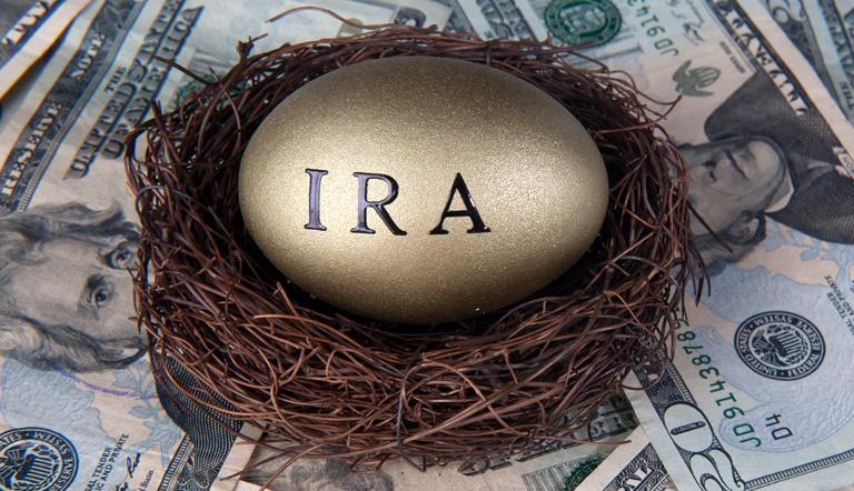 IRA stamped on a golden egg sitting in a nest on to of a pile of $20 bills