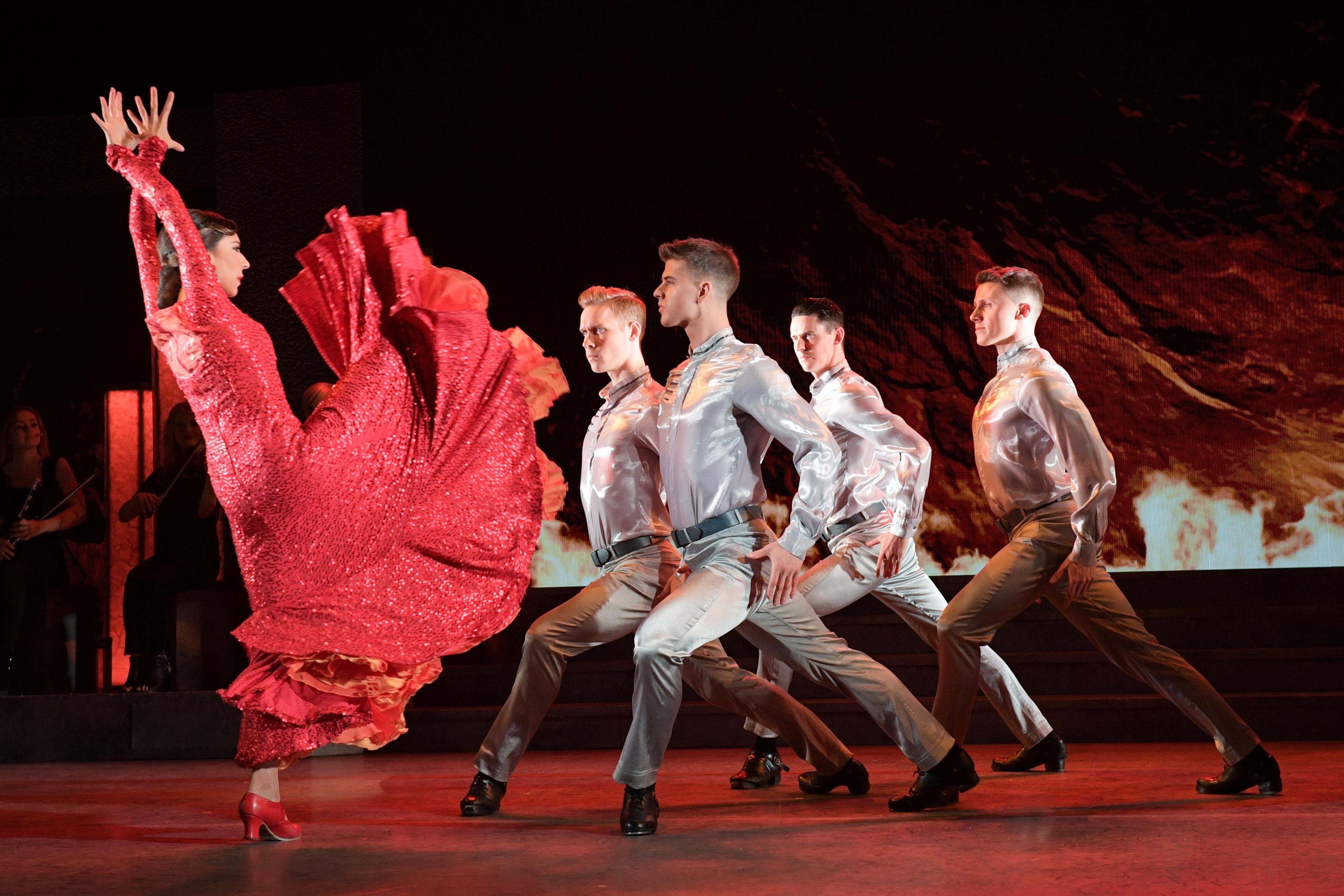 image from Firedance, a flamenco sequence with a woman in a red dress and four men in silver shirts