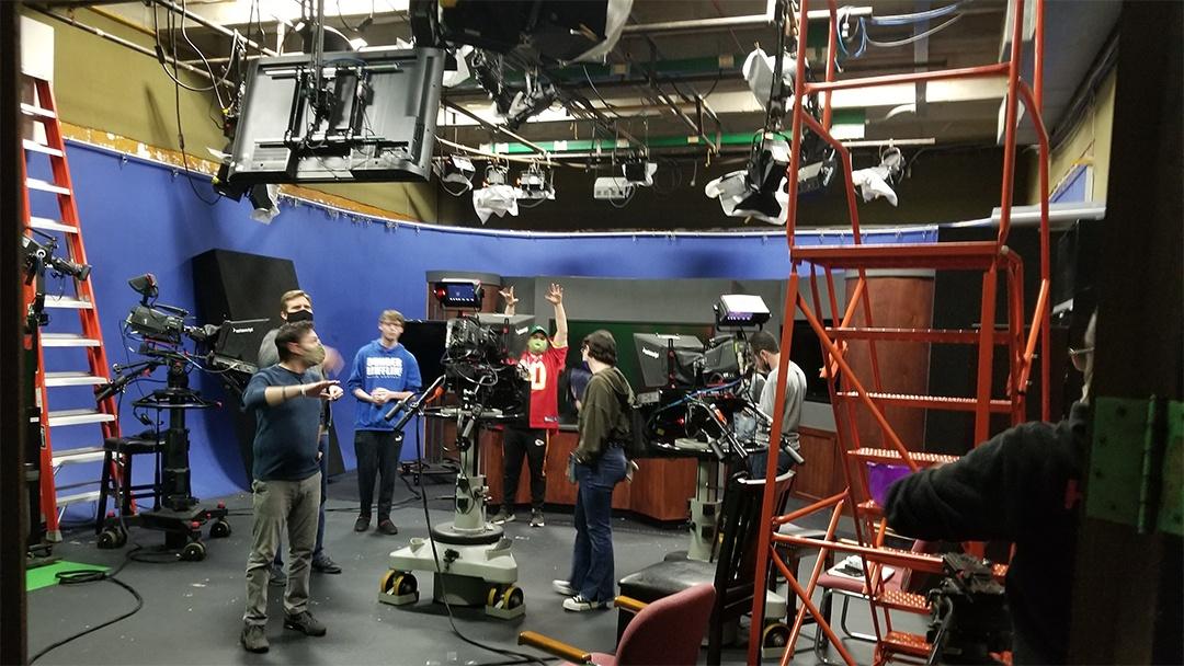 Behind-the-scenes of the recording studio with student employees setting up film equipment.