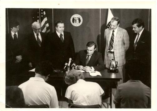 Governor Joseph Teasdale signs S.B. 835. To his left are Senator Harold Caskey and manager John Bradley.