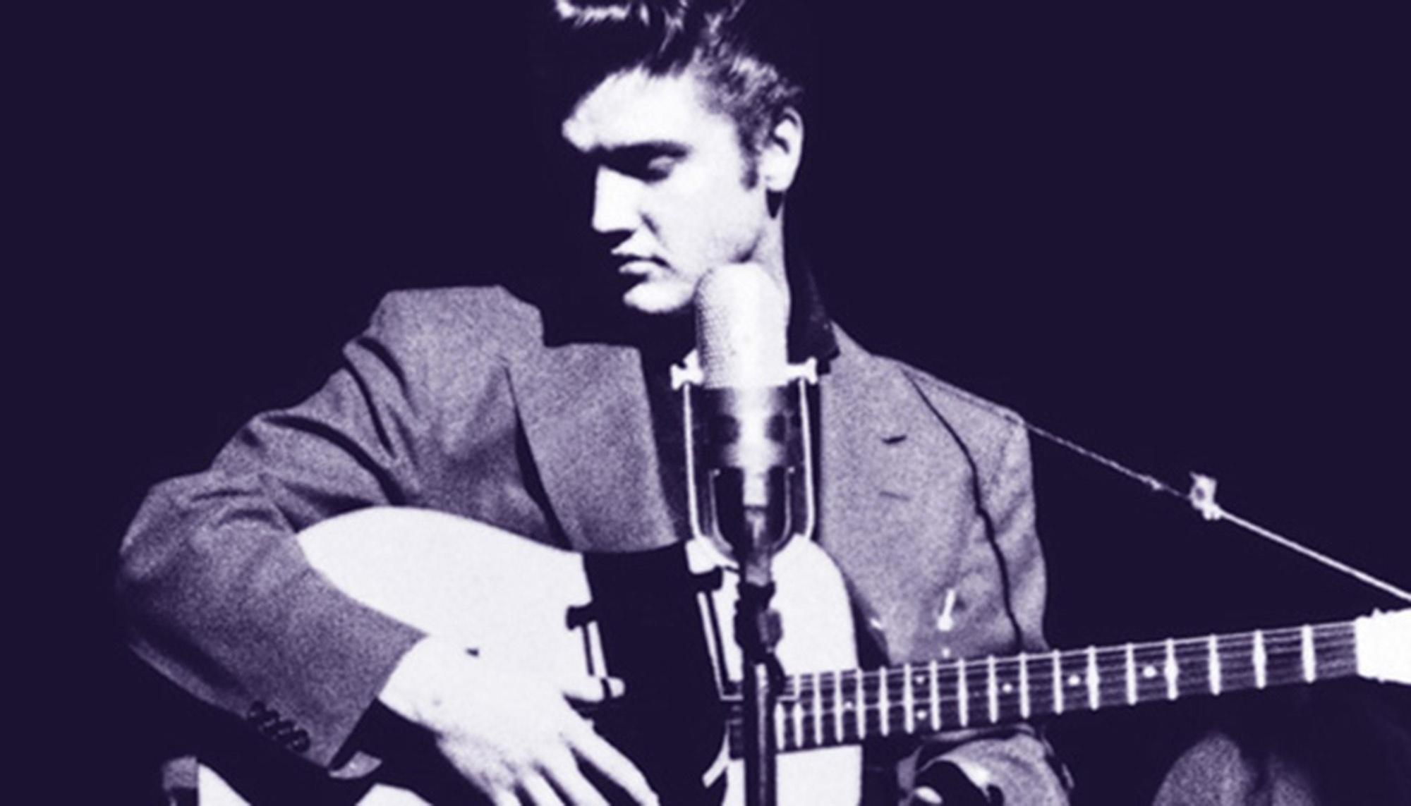 Elvis playing the guitar while in front of a microphone.