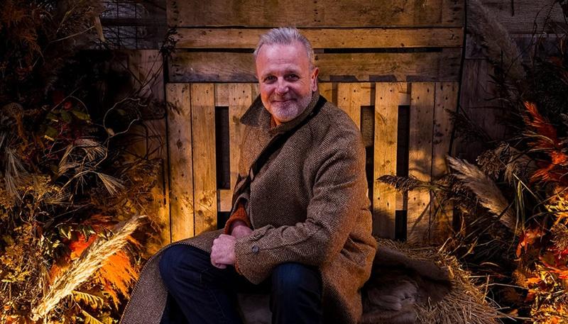Michael Londra sitting on a haybale in an Autumn setting.