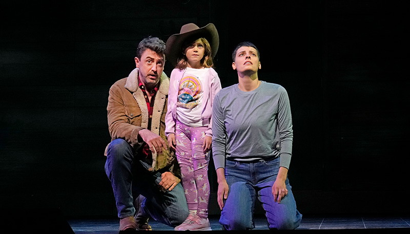 Emily D'Angelo sitting and performing on stage with her two co-stars in the opera.