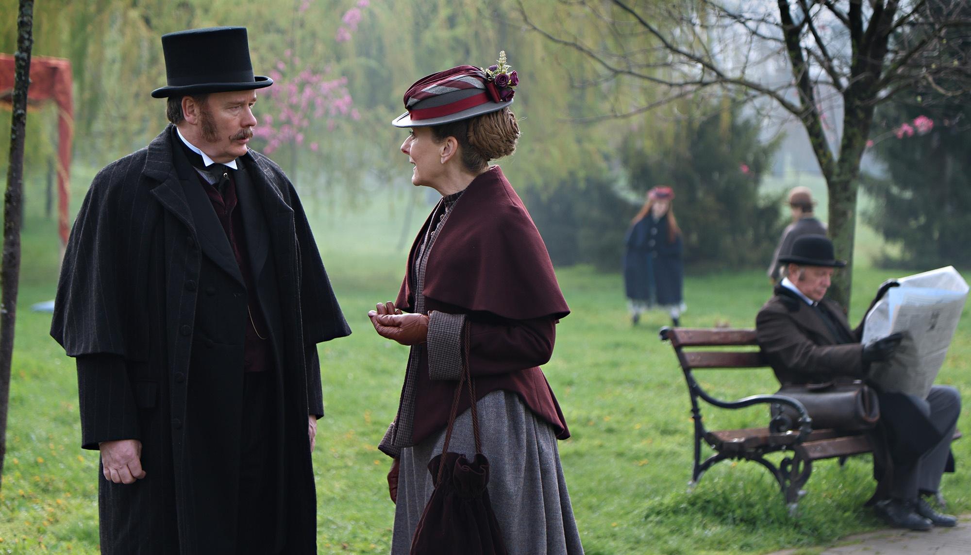Miss Scarlet talking to a gentleman while in a beautiful park.