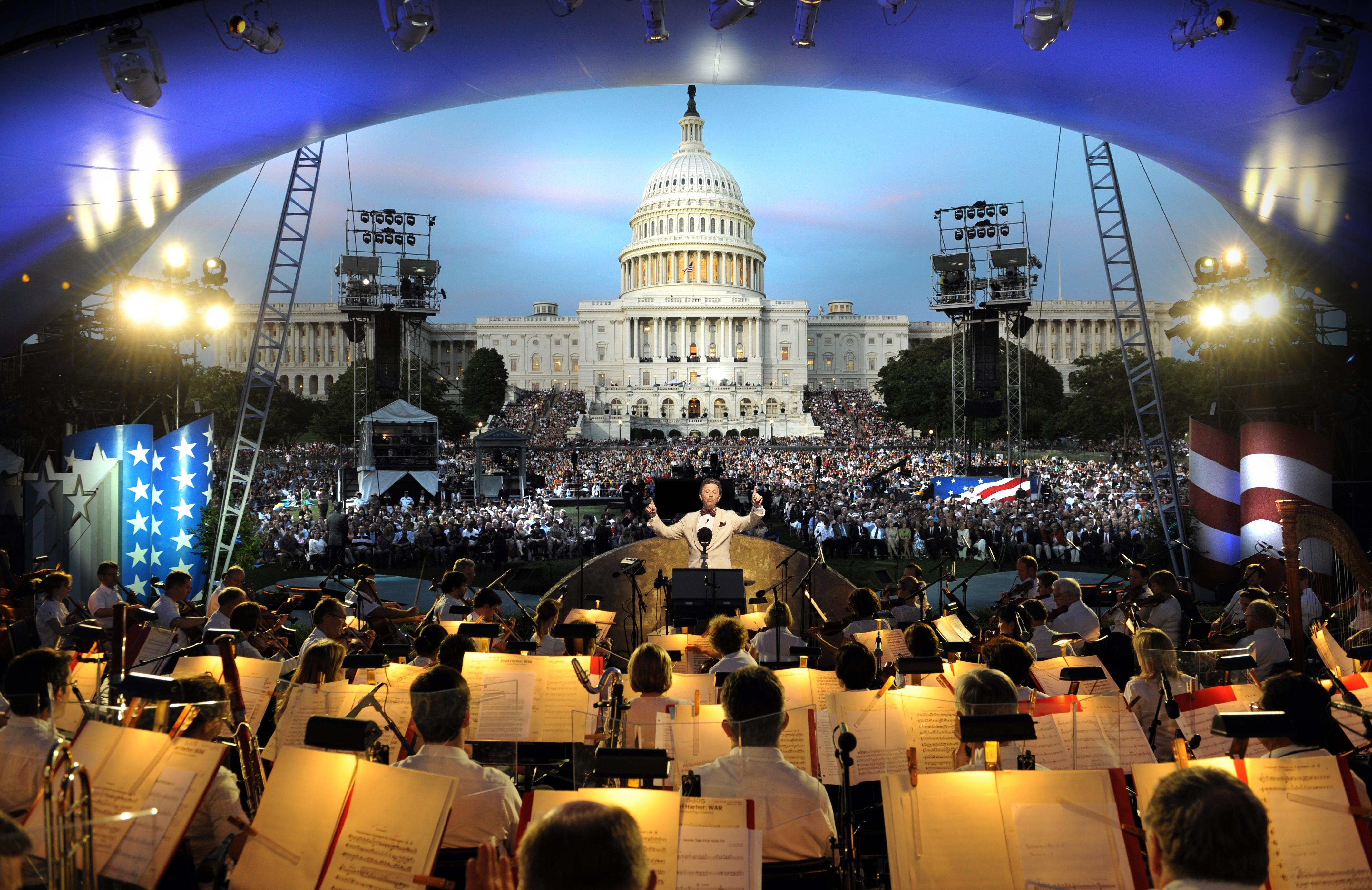 An image of Jack Everly conducting the National Symphony Orchestra before the on-site audience on the West Lawn of the U.S. Capitol.