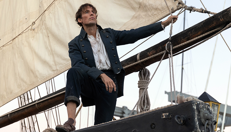 Edmond Dantes stands on a ship looking out into the distance.