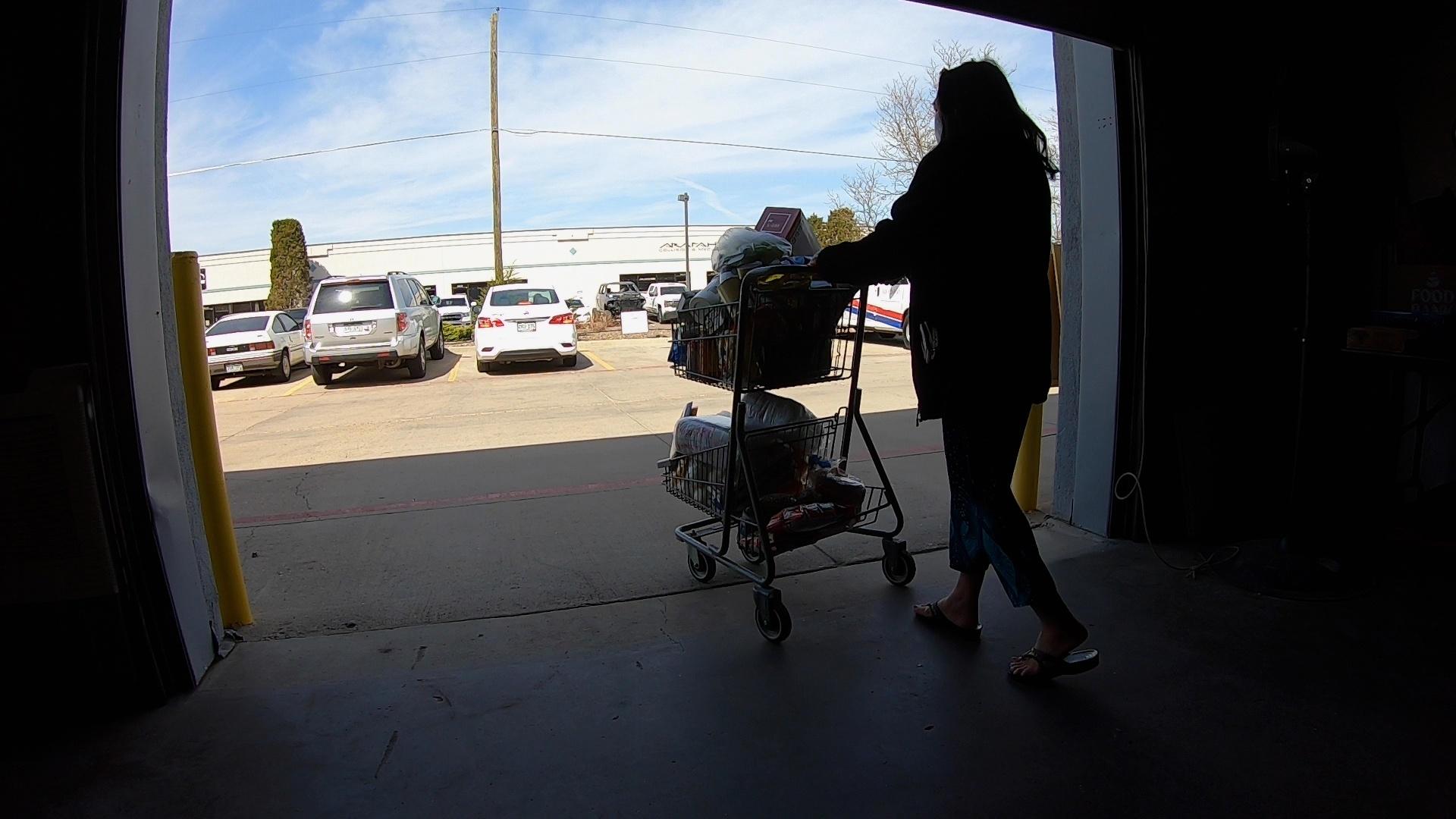 A shopper at Food Connect Colorado leaves the free grocery store with a cart full of food in Aurora.