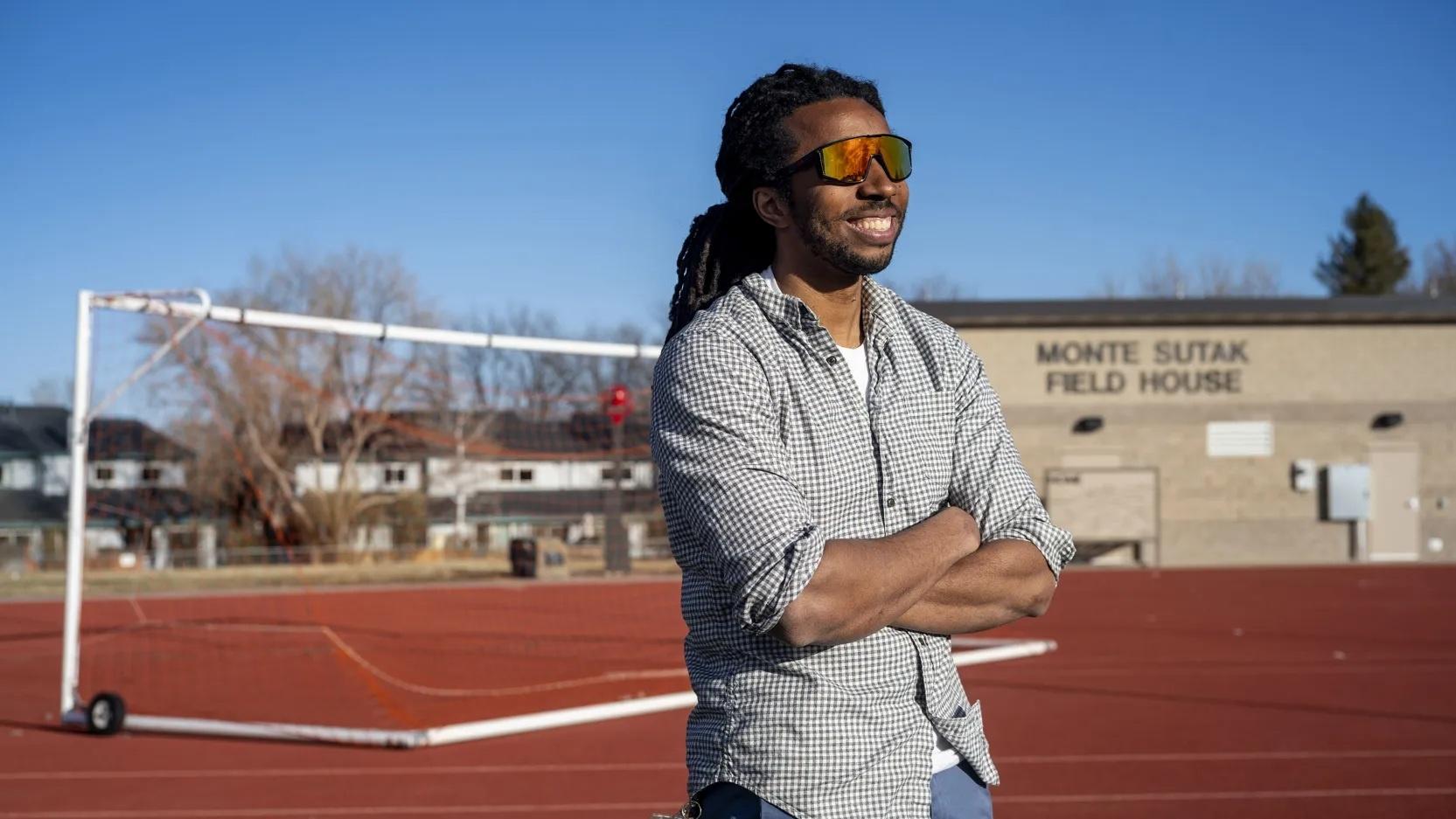 Eddie Taylor stands at the track of Centaurus High School in the Boulder Valley district, where he coaches track and field and teaches chemistry.