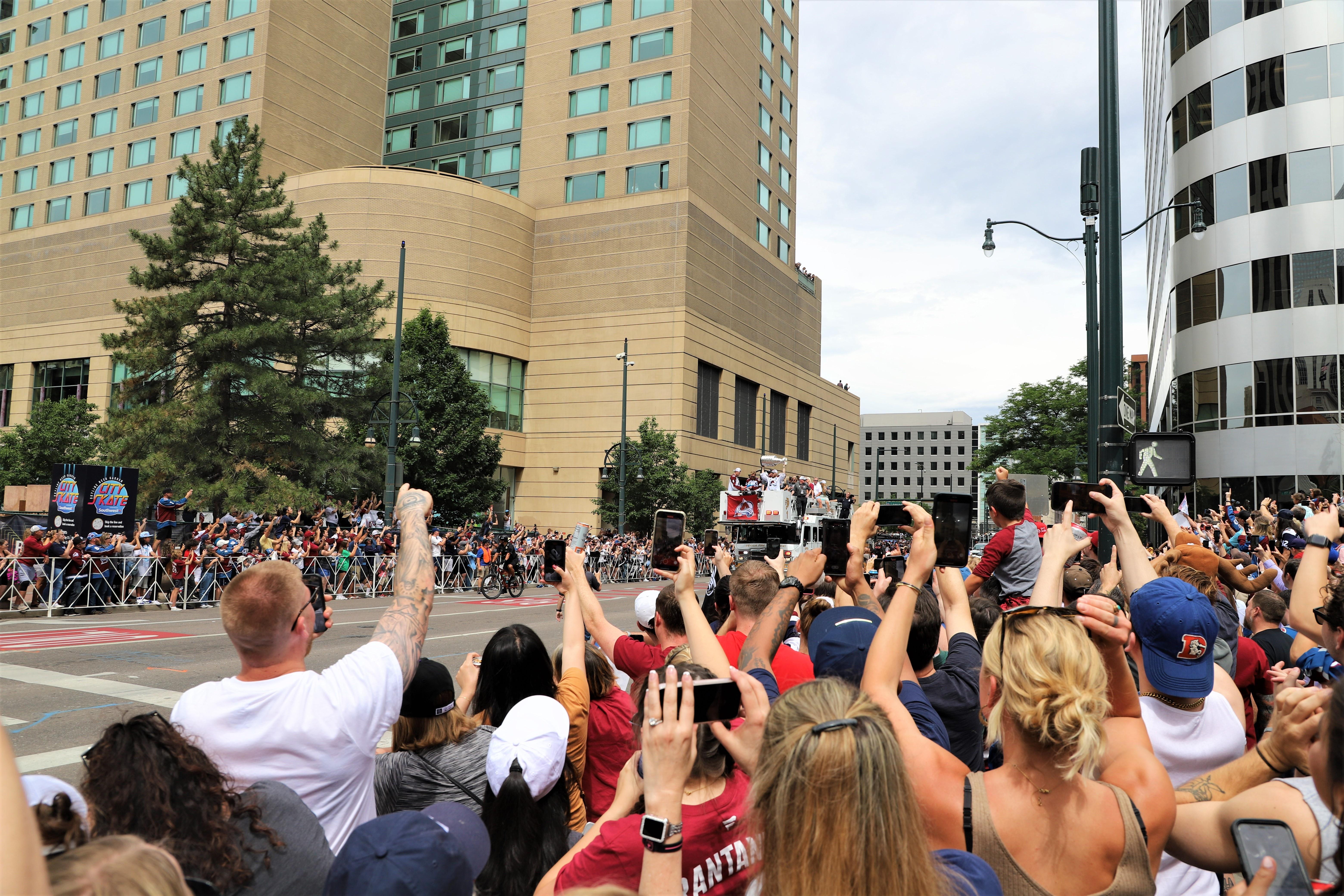 Fans reach out to touch the Stanley Cup as Colorado Avalanche defenseman Bowen  Byram, front, brings it to the crowd during a rally outside the City/County  Building for the NHL hockey champions