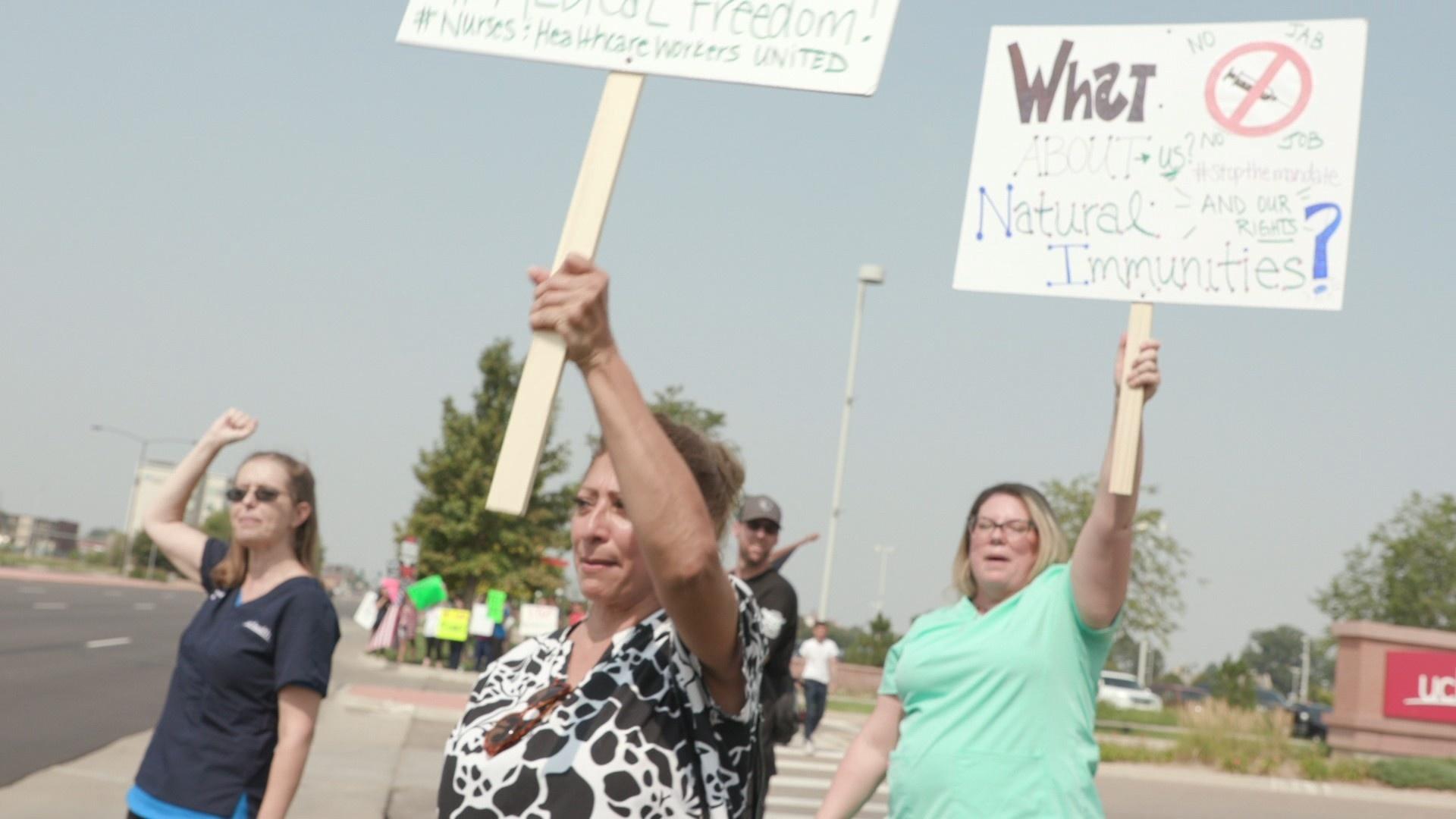 Stephanie Thorpe, far left, and Kinley Queen-Thompson, far right, protest with others against COVID-19 vaccine mandates outside the the UCHealth Anschutz Medical Campus, August 9.
