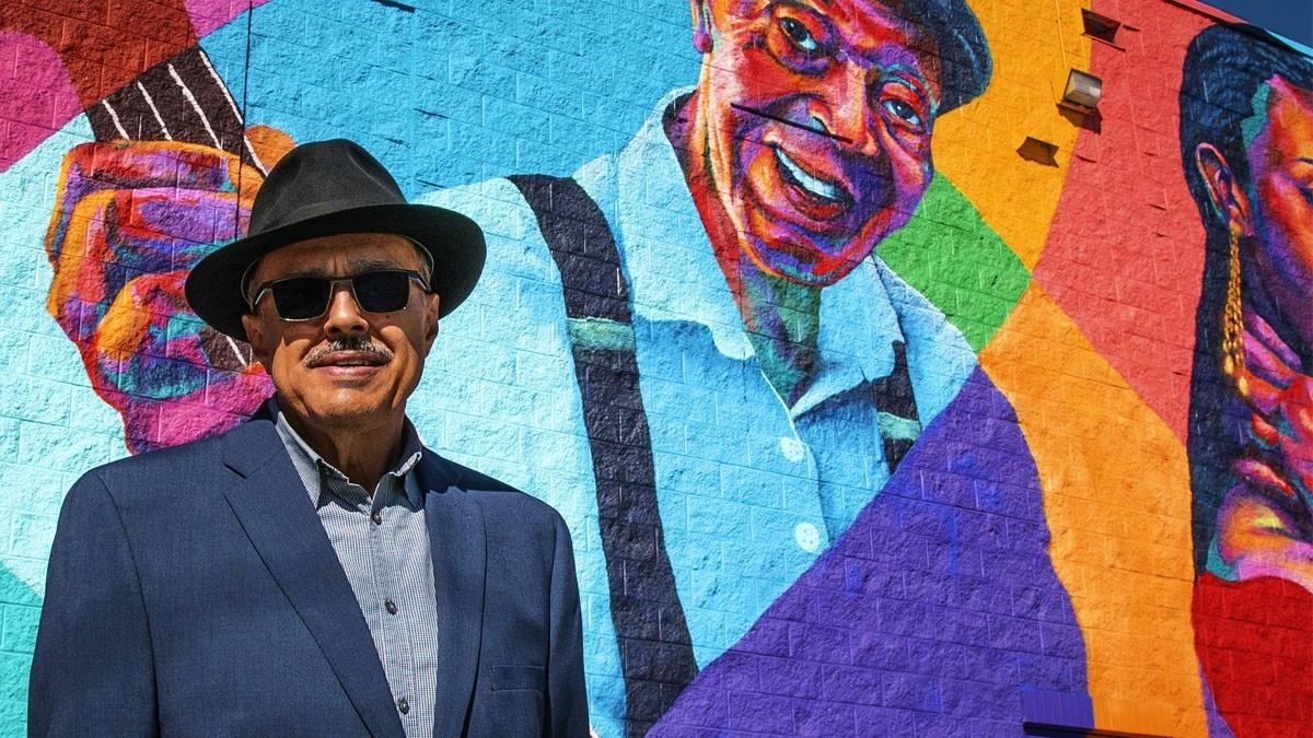 KUVO general manager Carlos Lando in front of a mural of Charlie Burrell in Denver's Five Points neighborhood.
