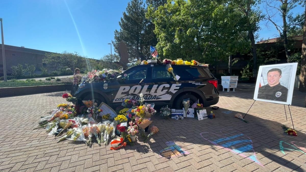 A tribute to Officer Dillon Vakoff outside the Arvada Police Station on Monday, Sept. 12, 2022. Flowers, posters and cards are surrounding a police cruiser.