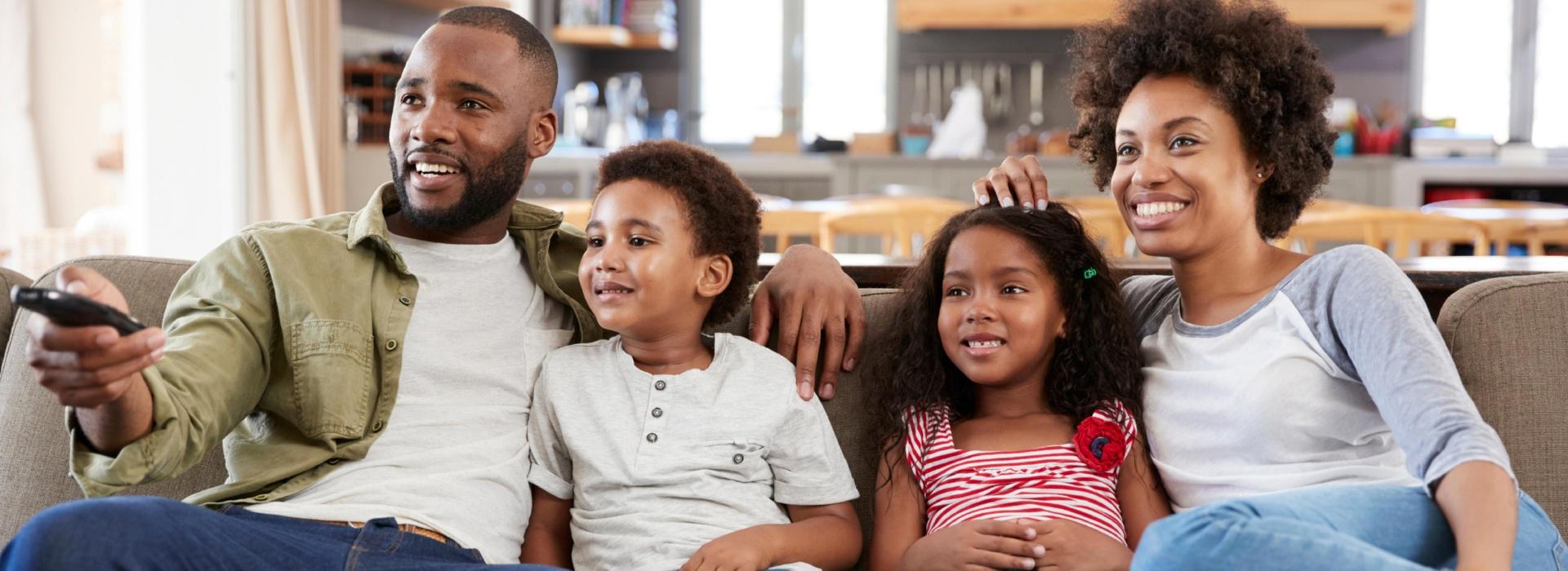 family sitting on couch watching television