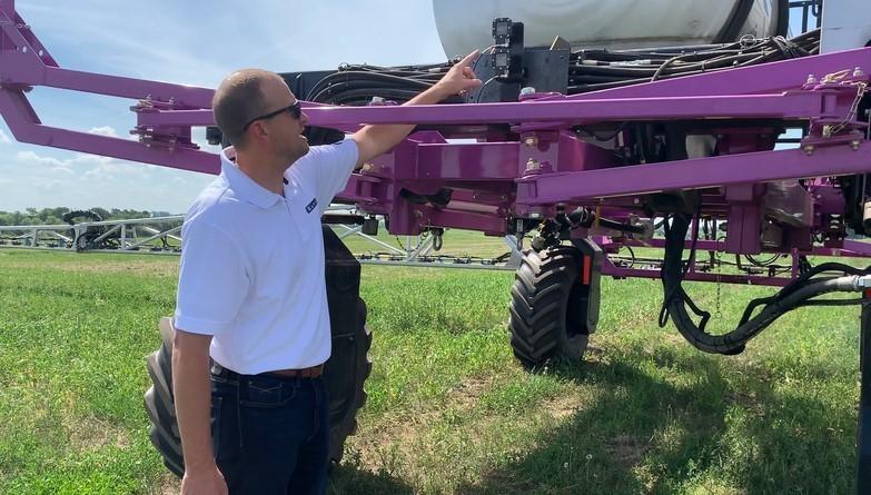 Many standing next to a sprayer. 