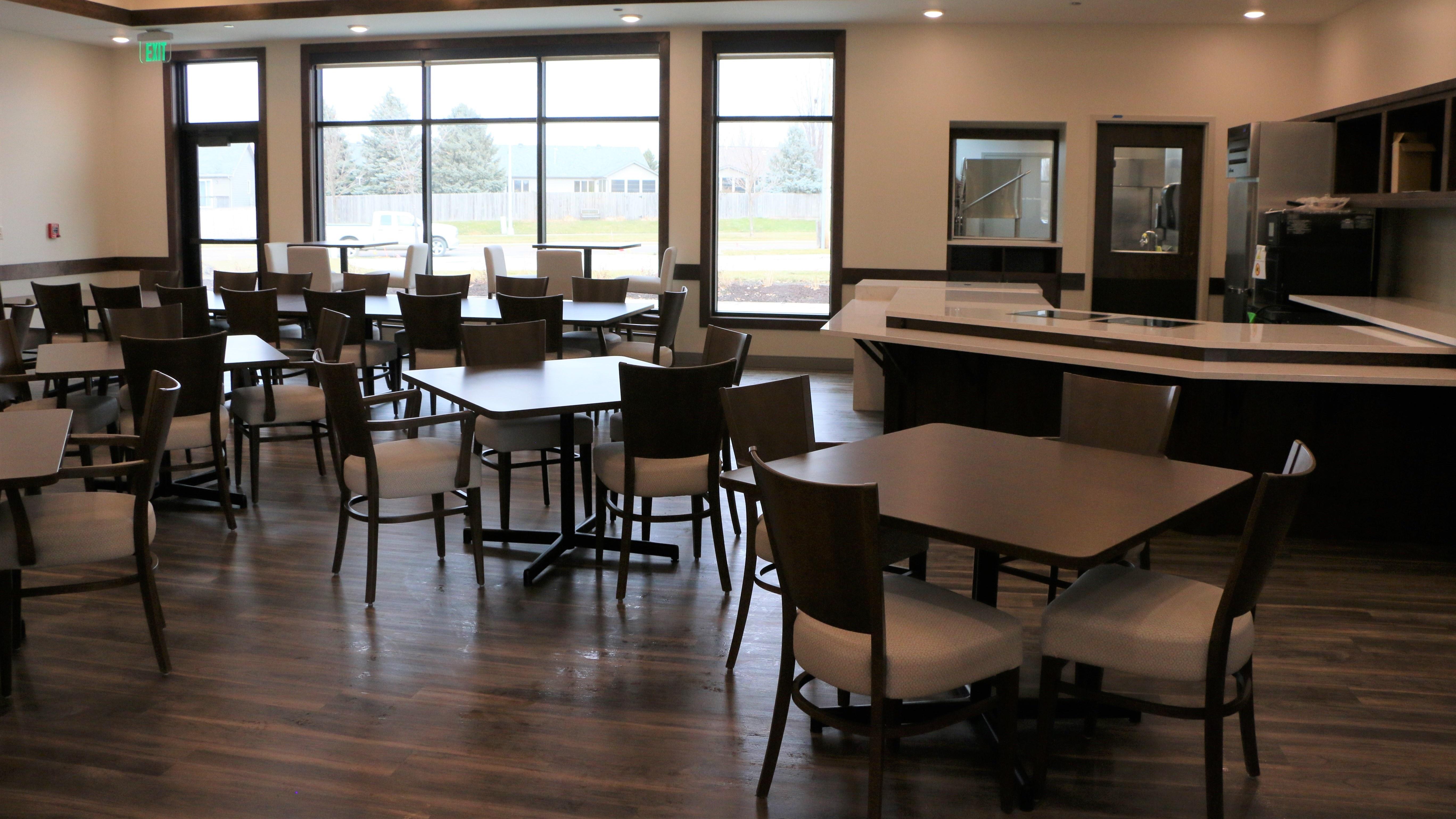 The empty dining room of the new Avera Addiction Care Center in Sioux Falls, with a large window, several tables and chairs.