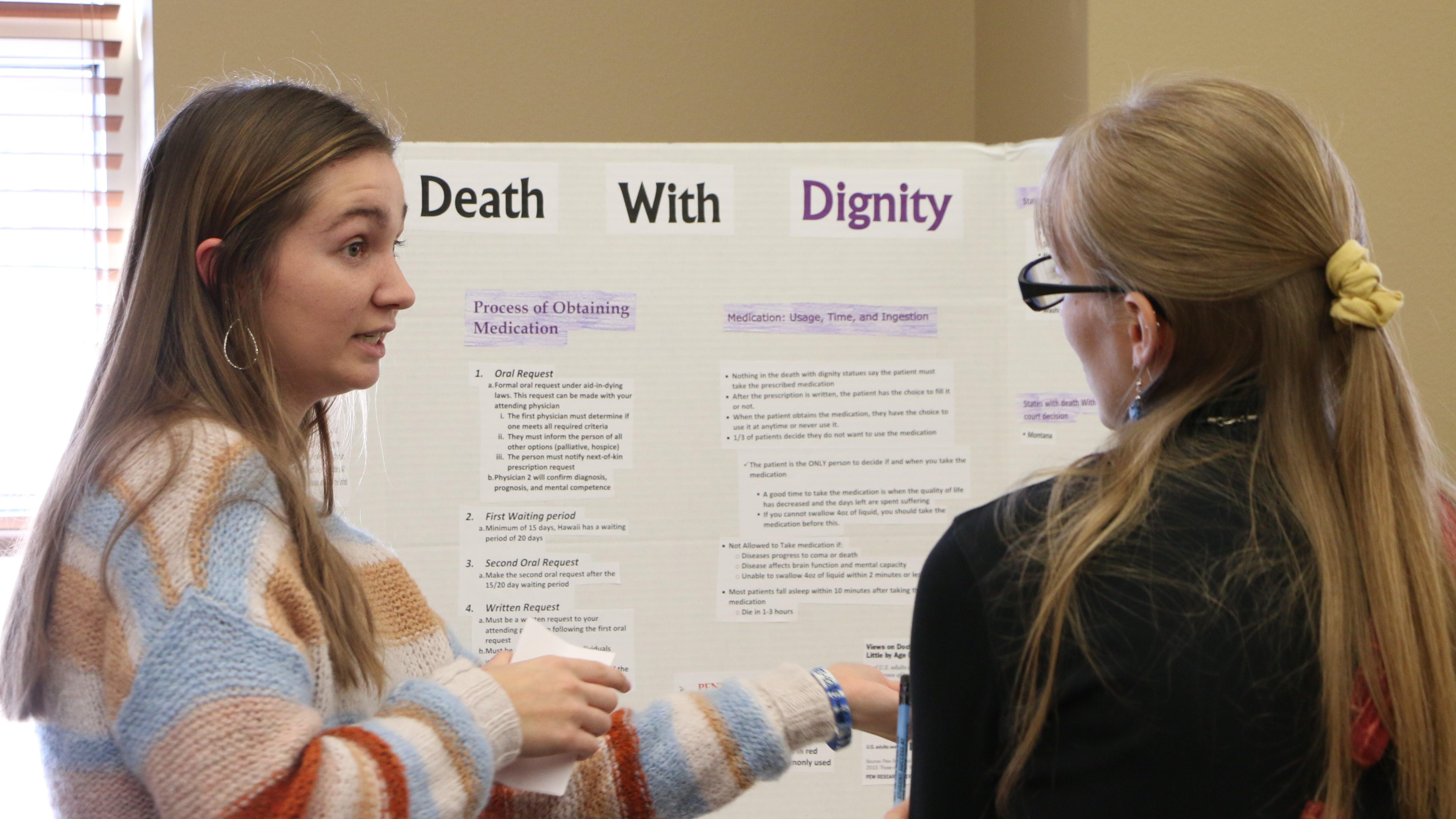 A DWU student presents her research on death with dignity to a visitor during the Death Café.