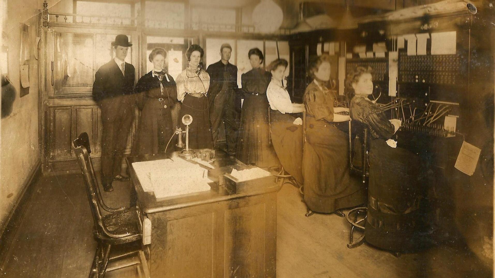 Decorative - Image of the Past series photo of three women at a switch board. Two additional men and three women are standing at the back of the room. 
