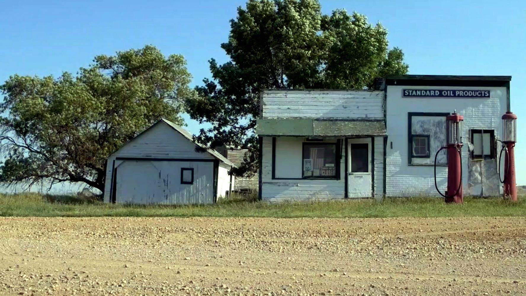 An abandoned gas station that has two Crandall gas pumps. 