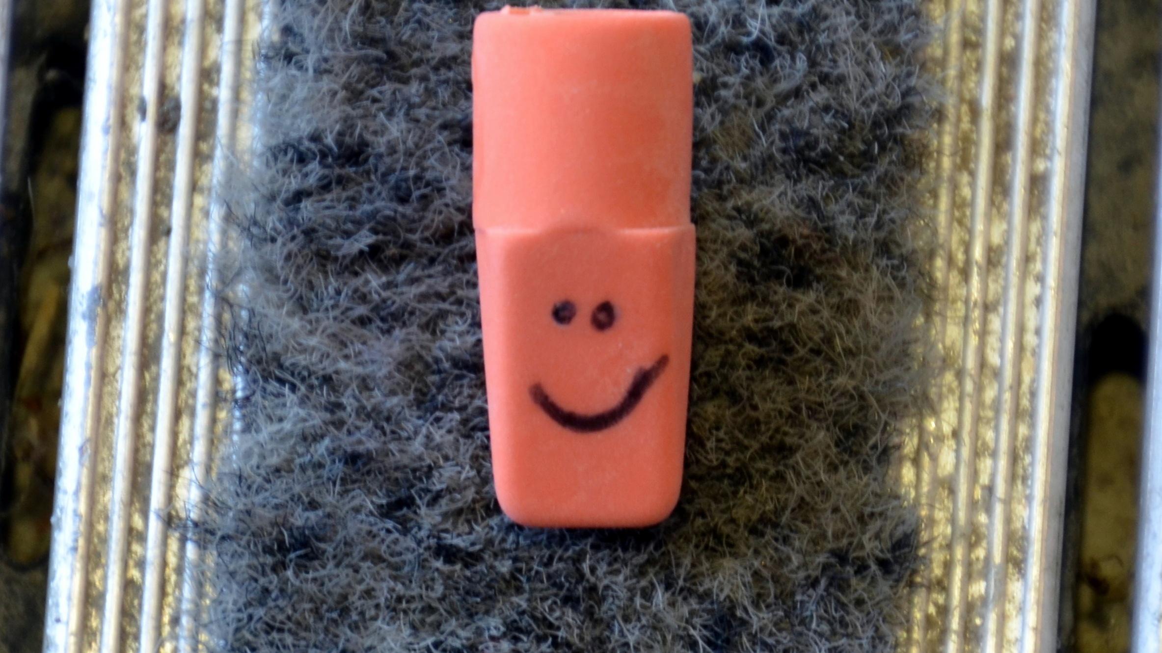 Pencil eraser with a smiley face drawn on it. 