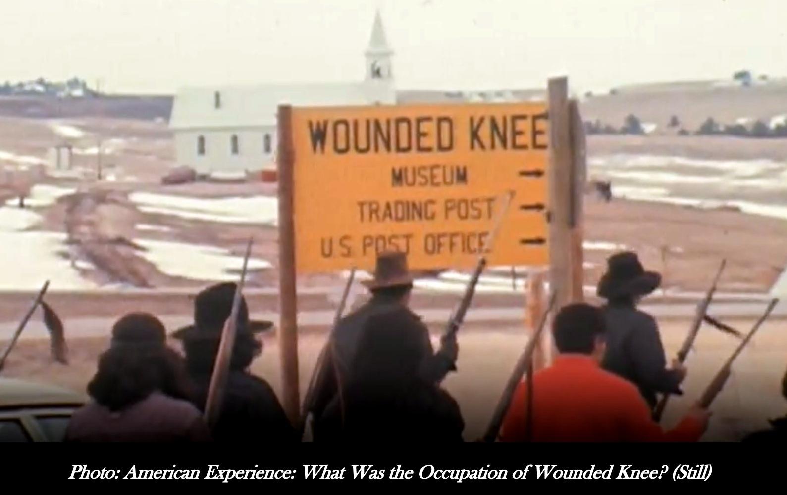This is a 1973 photo of armed militant American Indian Movement members near a Wounded Knee sign. 