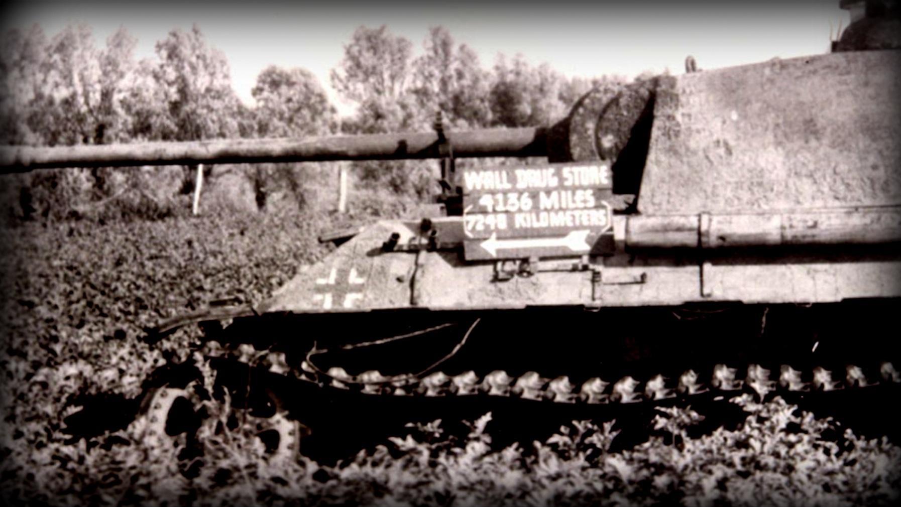 Archival photo of a tank with a Wall Drug Store sign on it. Its say 4,136 miles to Wall Drug. 