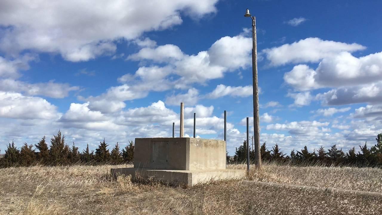 A large cement-like structure in the middle of a grassy area. 