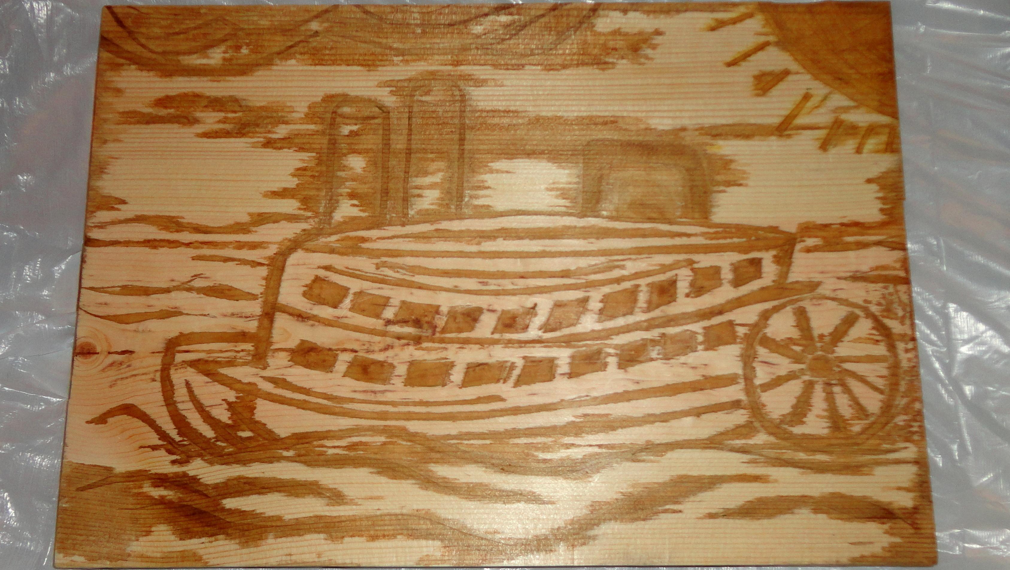 Photo of an art project - an image of a steamboat is stained onto a piece of wood. 