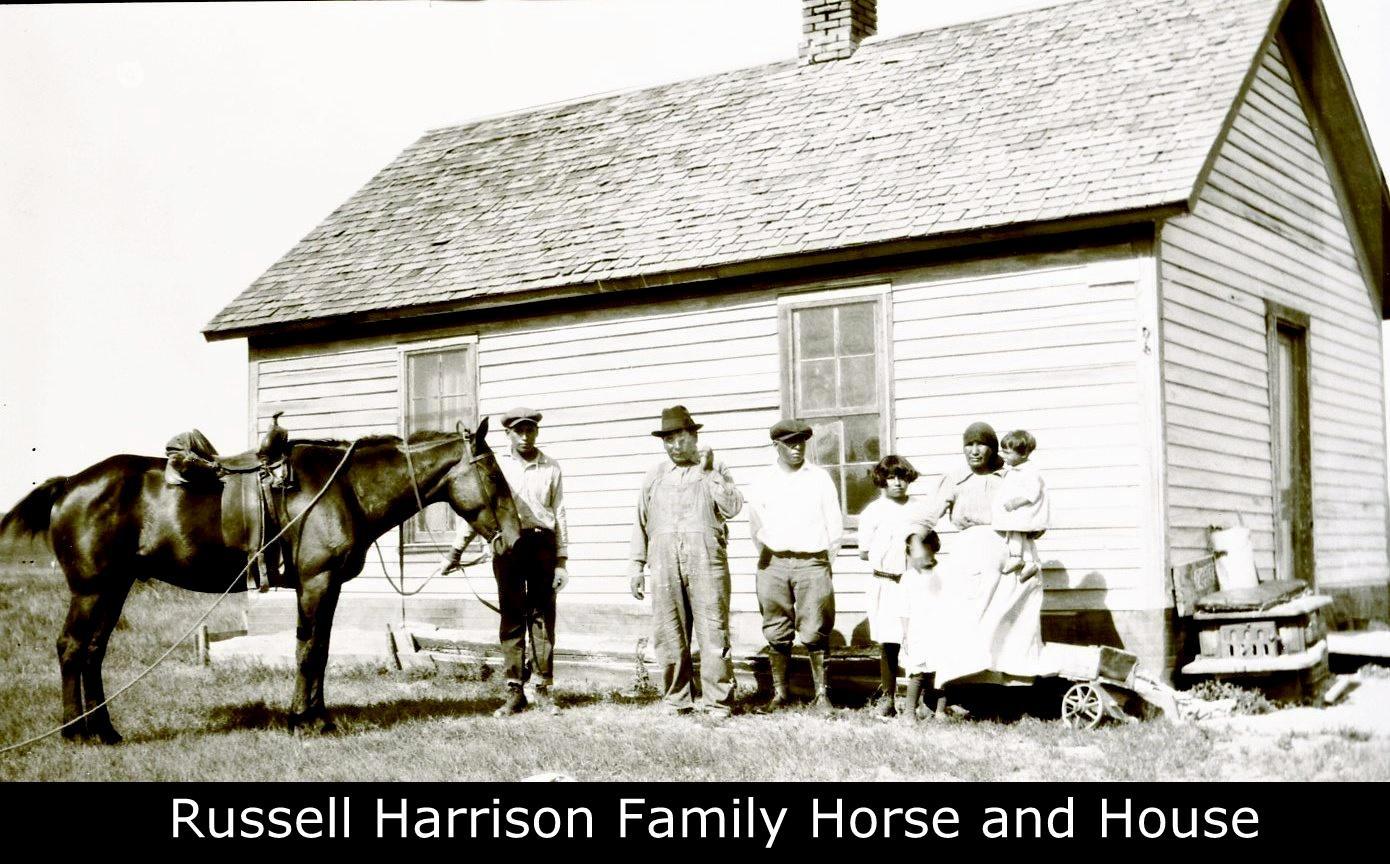   An archival photo of a family with a horse standing before a house.