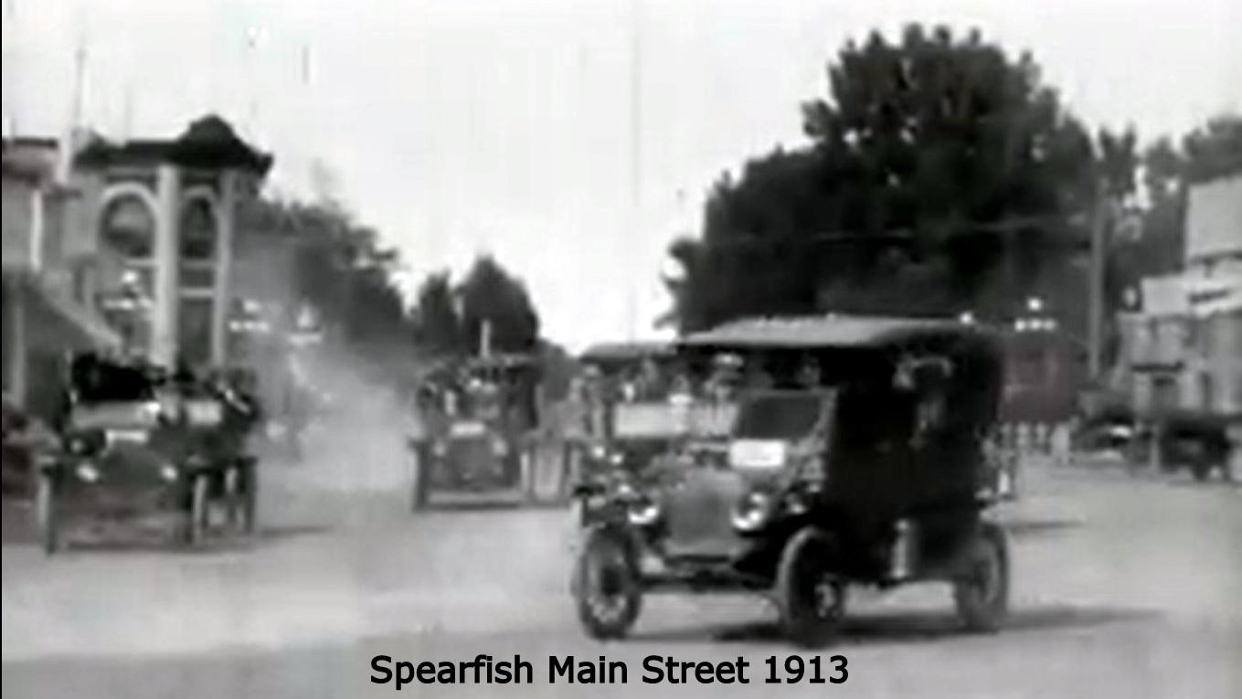 Spearfish Main Street in 1913.  Four Model T cars are driving on the street.  