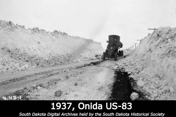 Decorative image from 1937 near Onida South Dakota that shows a maintainer removing snow from a road. Snow is piled up approximately ten to fifteen feet on each side of the road.  