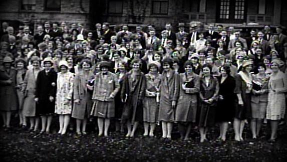 Archival photo of many students standing in front of a school. 