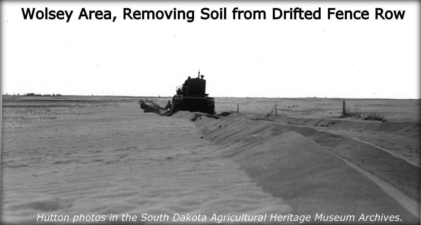 Dust Bowl photo of a bulldozer plowing sand from drifted fence row.