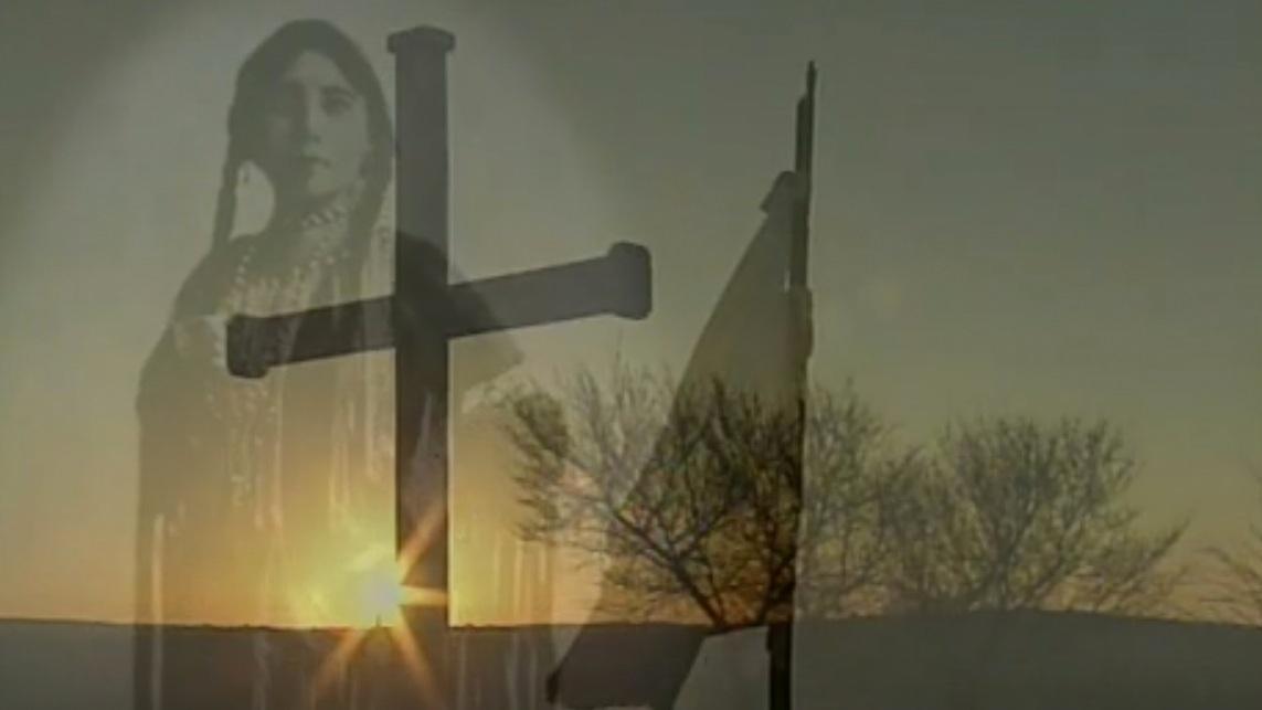 Lost Bird of Wounded Knee Logo: There is a faint image of a Native American woman standing in front of a cross, with the sun setting in the background. 